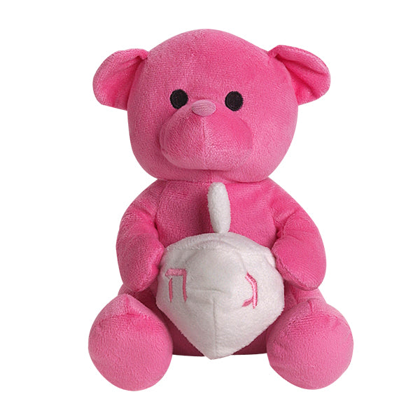 A pink plush teddy bear sitting and holding a white dreidel (Spinning top)